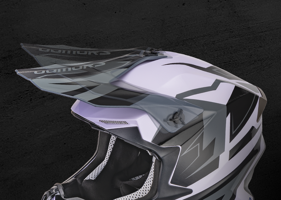 A close-up studio shot of a motocross or off-road full-face helmet in white, gray, and black, with a clear visor and interior padding visible against a dark textured background.