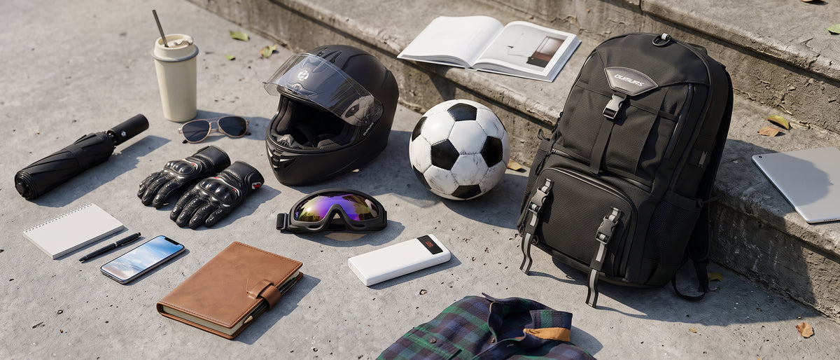 Black OUMURS backpack beside a motorcycle helmet, gloves, goggles, soccer ball, and travel essentials.