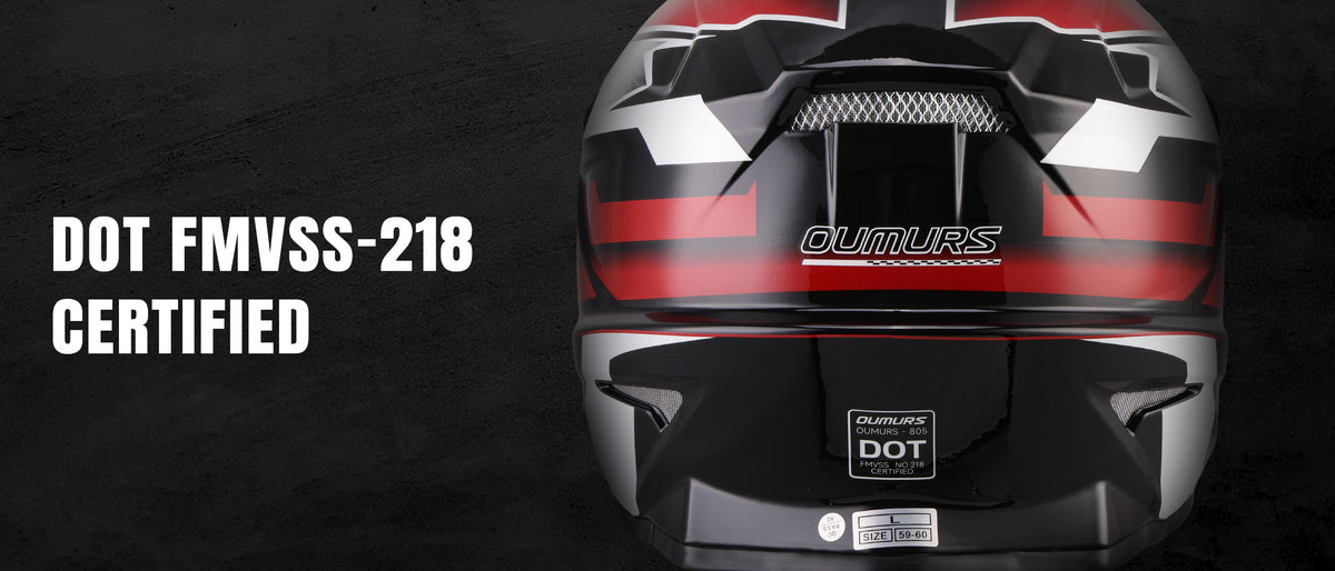 A full-face motorcycle helmet shown from the front on a dark textured background, with white text at the top reading 'DOT FMVSS-218 CERTIFIED'. The helmet is glossy black with silver geometric accents and a visible DOT certification badge on the lower front.