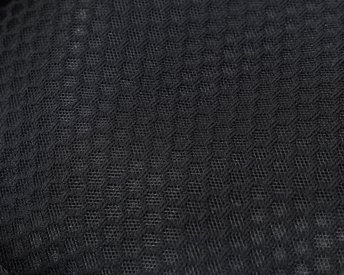 Close-up of a black textured mesh fabric with a repeating geometric pattern.