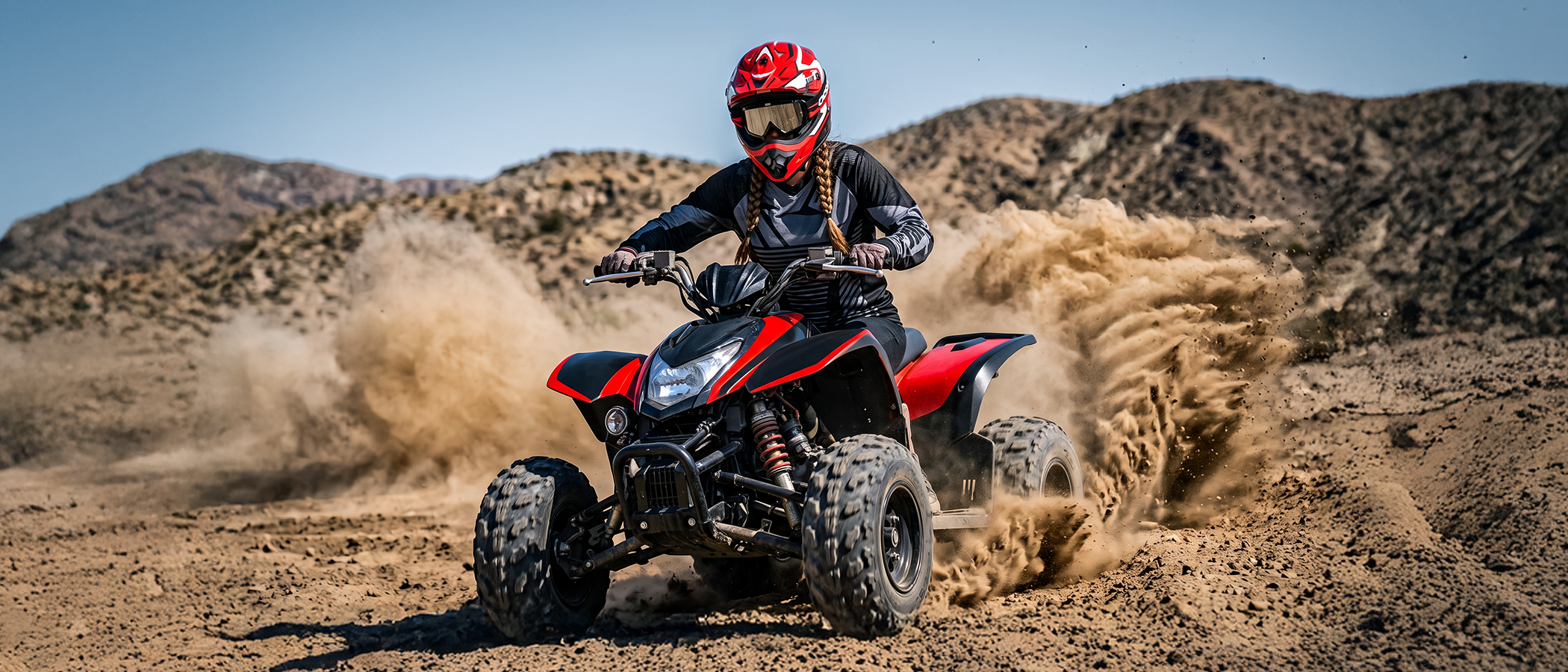A woman wearing an Oumurs 805 Engine Red off-road helmet rides an ATV through the desert while kicking up dust.