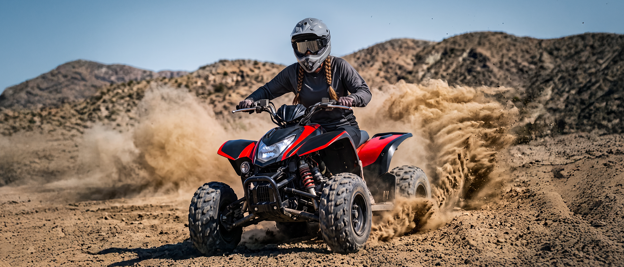 A woman wearing an Oumurs 805 Gray off-road helmet rides an ATV through the desert while kicking up dust.