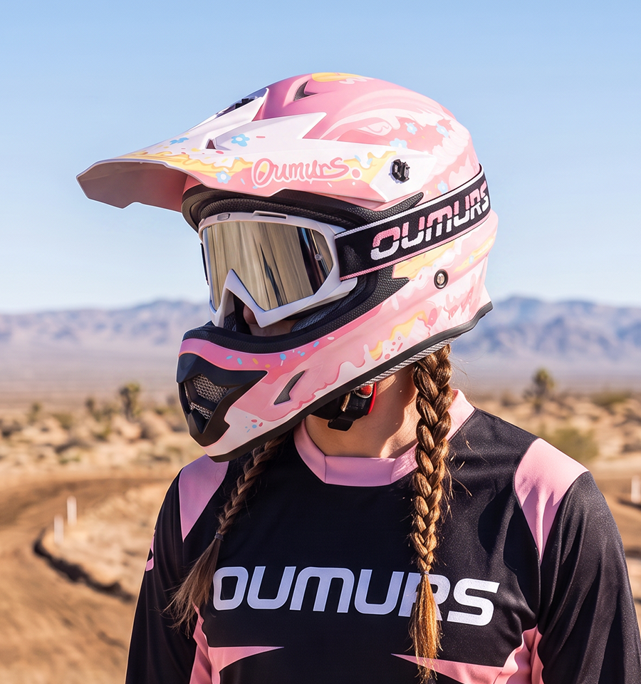 A rider wearing an Oumurs 805 Pink off-road helmet with UV-protective goggles.