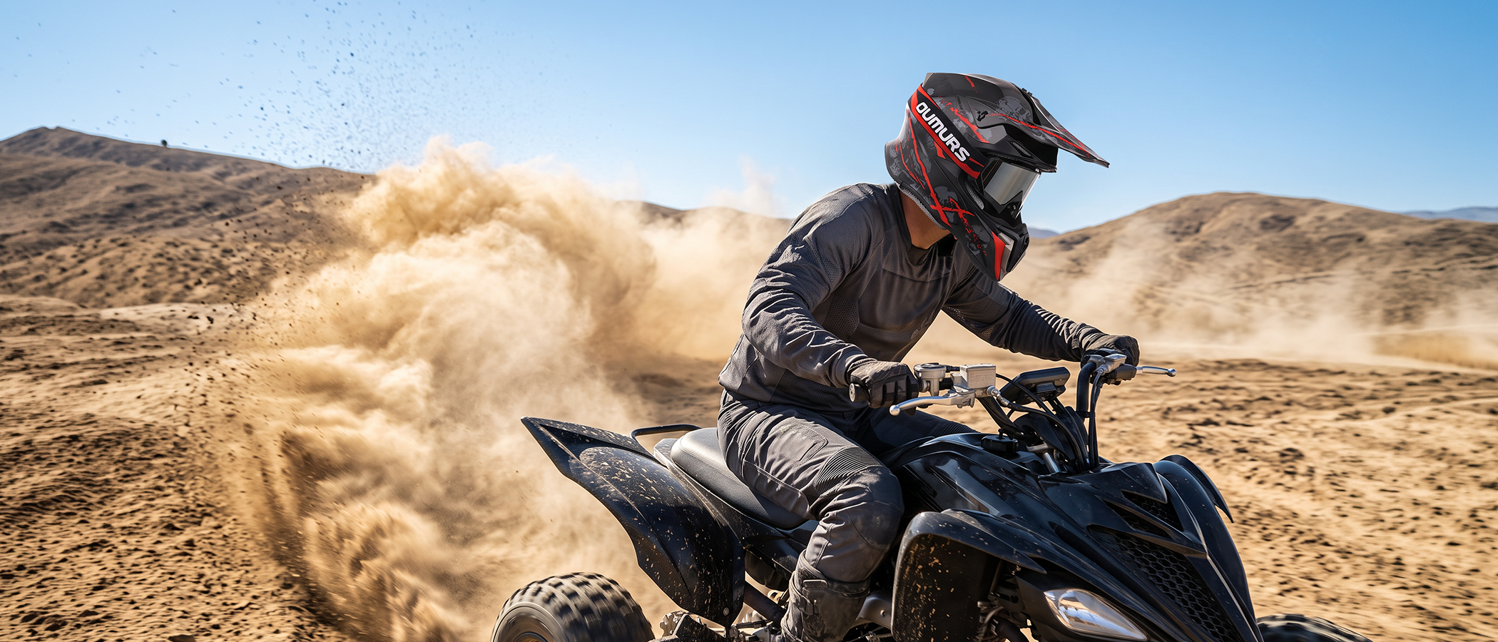 A person wearing an OUMURS 806 Red Skull off-road helmet and protective riding gear operates an ATV in a dusty desert, kicking up a large cloud of sand.