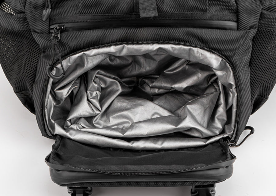 Open separate shoe compartment with gray lining at the bottom of a black motorcycle backpack.