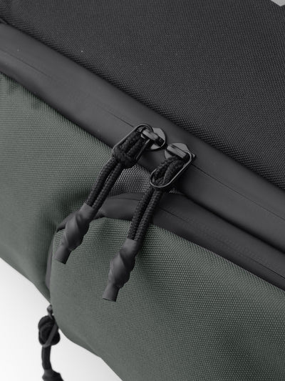  Close-up of dual zipper pulls and dark green fabric on the Oumurs motorcycle backpack.