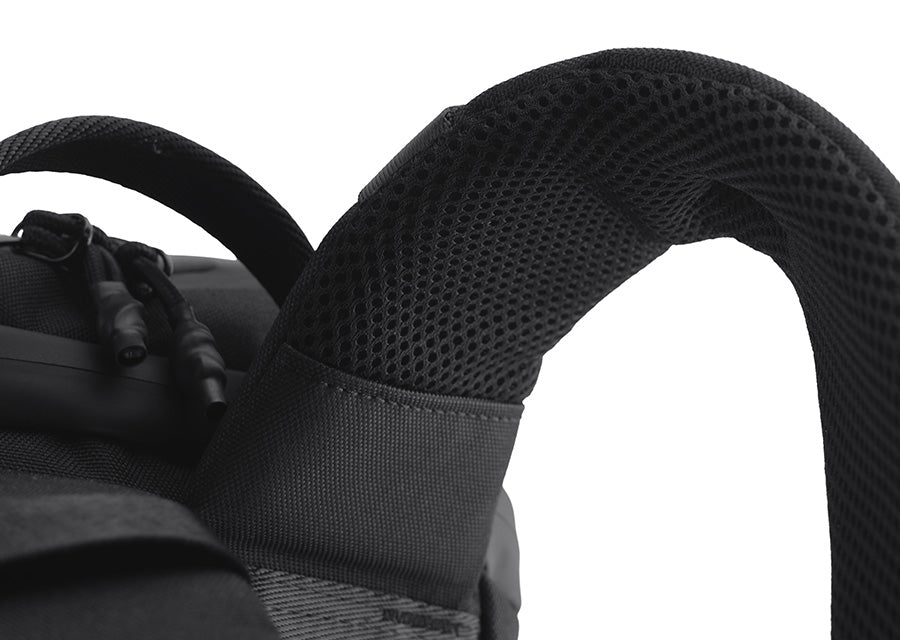 Close-up of a black backpack shoulder strap with a breathable mesh back panel and padded fabric, shown against a white background.
