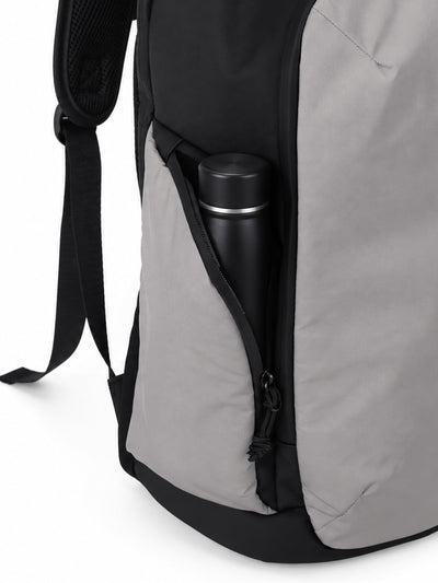 Close-up of a gray and black backpack showing a side pocket with a black insulated bottle inside, on a white background.