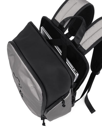 A black and gray backpack shown from an angled top-down view, with its main compartment open to reveal a silver laptop inside. The backpack features padded shoulder straps and a clean white background.
