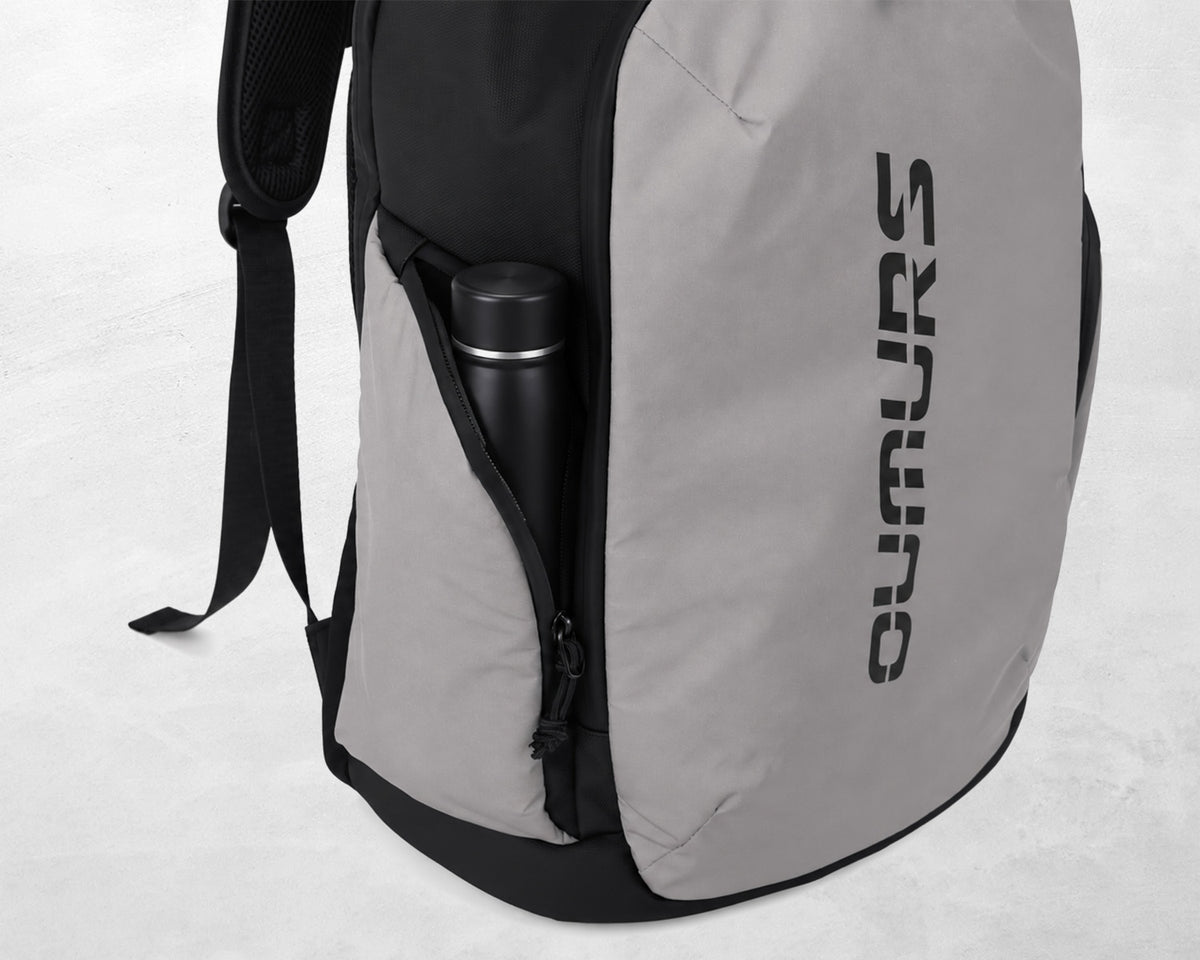 A gray and black backpack with a vertical black 'OUMURS' logo on the side, featuring a side pocket holding a black bottle, set against a light gray background.