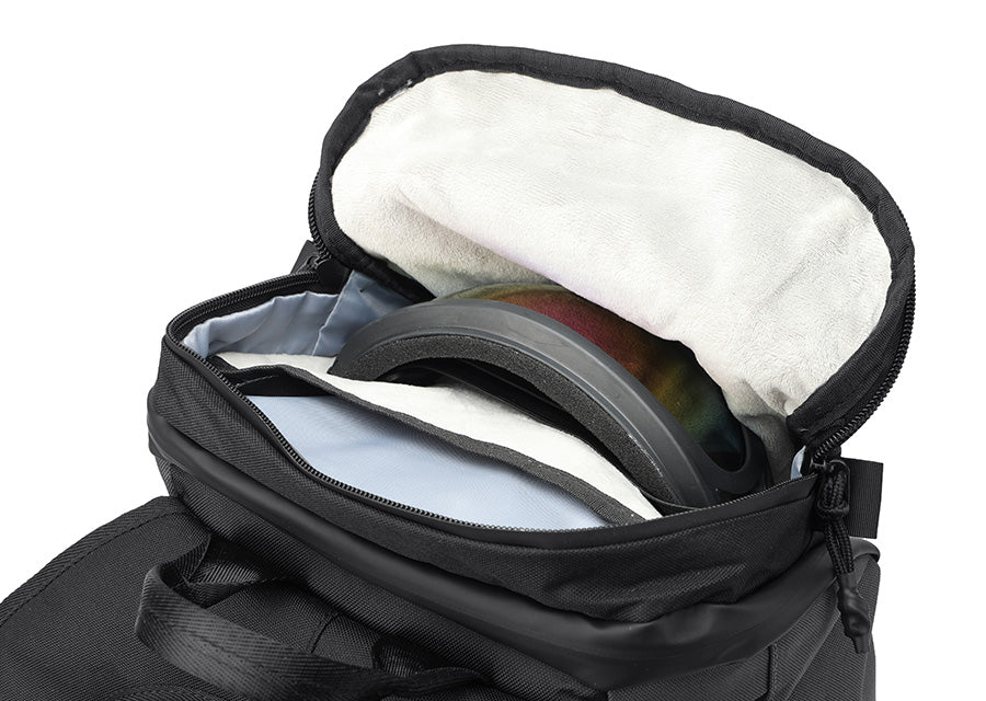 Top velvet-lined pocket: OUMURS motorcycle backpack with an open velvet-lined top pocket holding riding goggles.